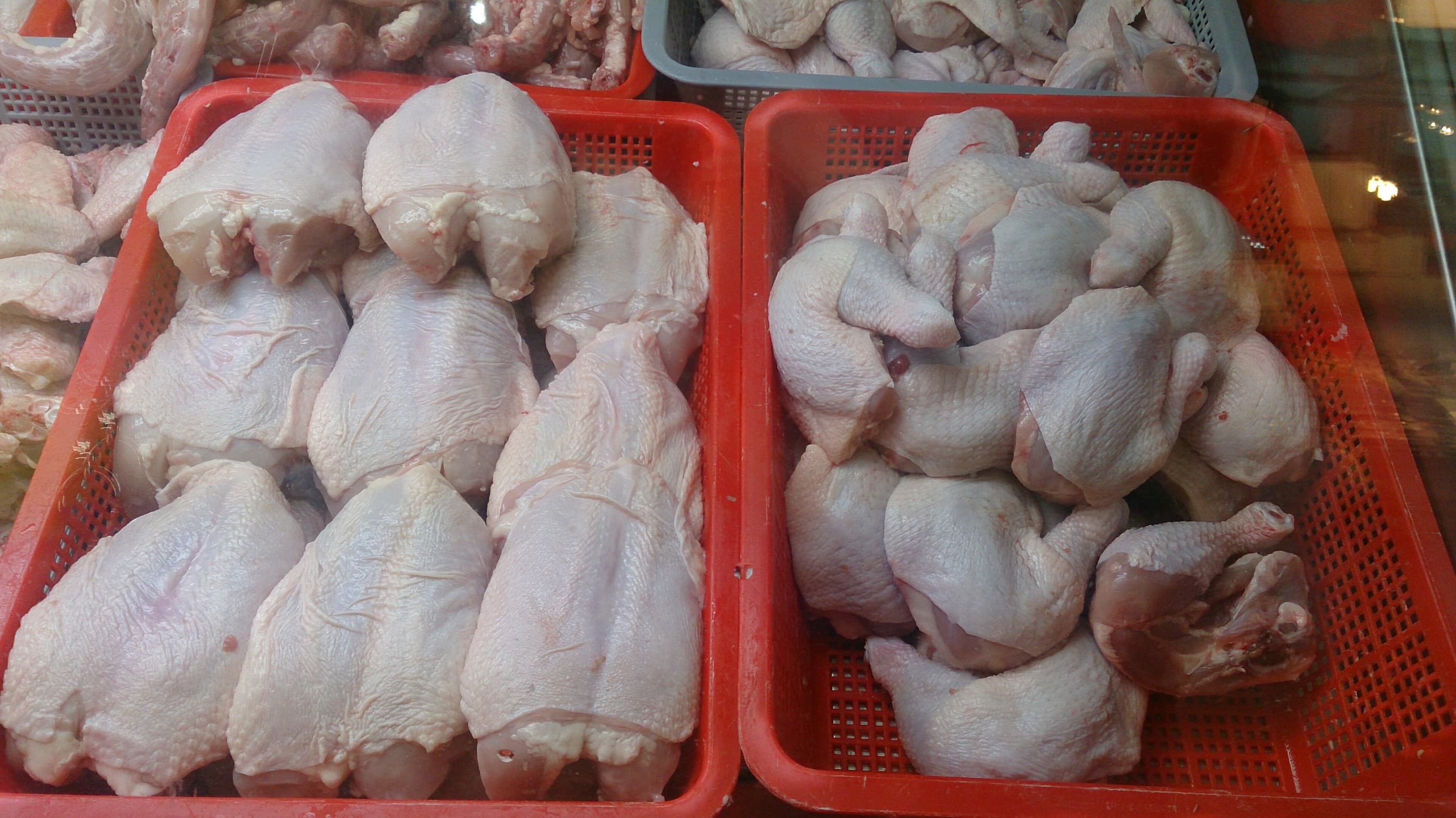 Whole fresh chickens in red crates at a market.