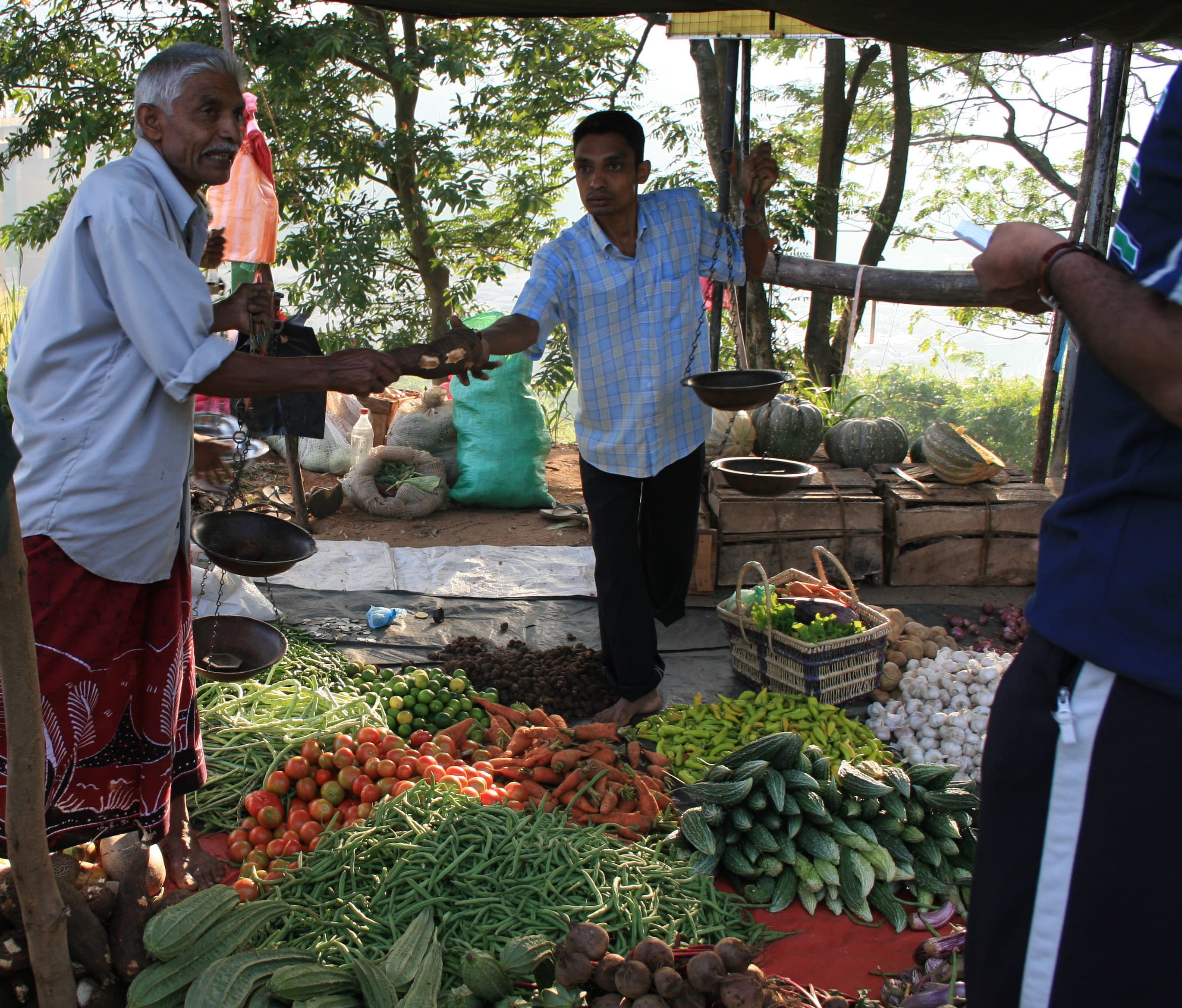 A stallholder weighing produce for a customer at Kandy market.